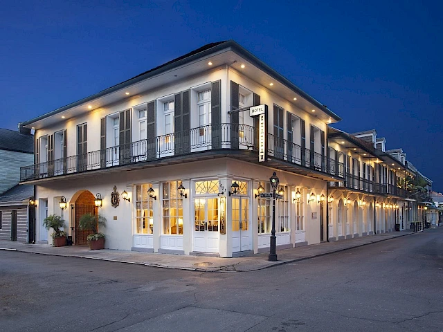 A two-story white building with black shutters and balconies, lit up at night.